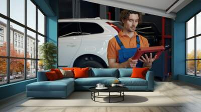 Portrait of serious male car technician looking at computer Wall mural