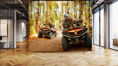 Two atv riders, speed race in forest, front view Wall mural