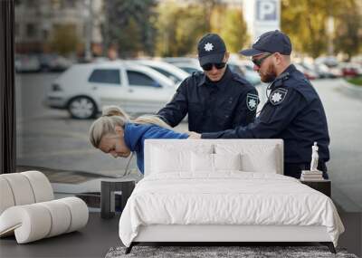 Two male police officers arrest female driver Wall mural