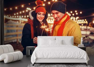 Winter evening, love couple with sparklers kissing Wall mural