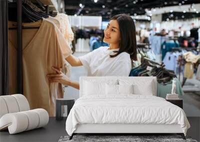 Woman choosing clothes in clothing store Wall mural