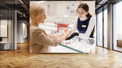 Woman trying on gold bracelet in jewelry store Wall mural