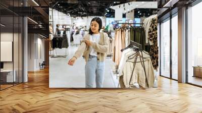 Young woman trying on cardigan in clothing store Wall mural