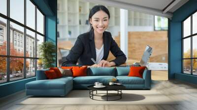 Businesswoman working on desk with laptop computer,Businesswoman using pen for note to do list concept. Wall mural