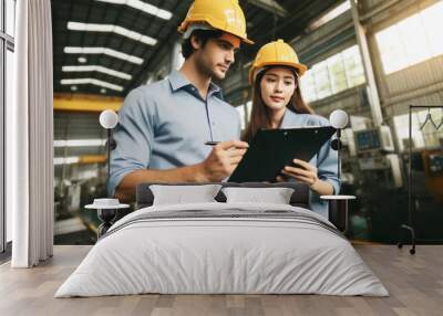 Two engineers in factory reviewing plans on clipboard Wall mural