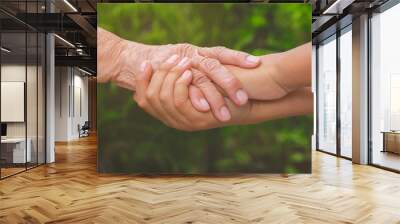 Old female hand holding young boys hands, care and support concept Wall mural