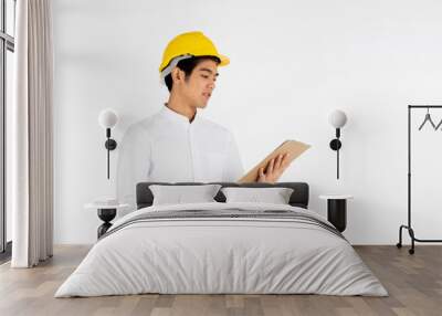 Portrait of handsome engineer wearing a yellow helmet at work and carrying a document on a white background Wall mural