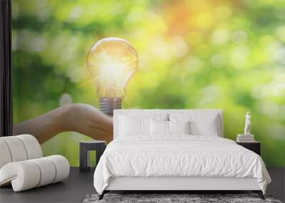 woman hand holding a light bulb energy concept natural blurred background Wall mural