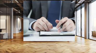 Businessman at the workplace drink coffee and looking some busin Wall mural