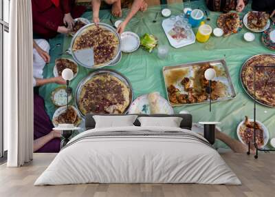 Family and friends gathering together at home for eating musakhan and chicken,sitting on floor in arabian traditional way of eating Wall mural