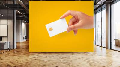 Woman Hand holding  blank credit chip card on Yellow background for business and finance Wall mural