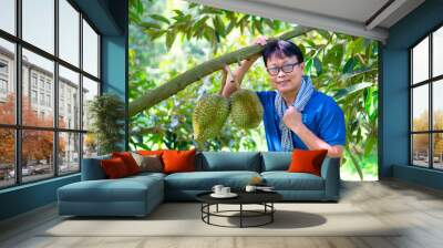 Asian man with durian in the garden.Asian man with durian tree in orchard garden,Thailand,asia. Wall mural