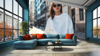 Mockup. Young woman wearing blank white crewneck sweatshirt in city street in sunny day. Mock up template for sweatshirt design, print area for logo or design. Wall mural