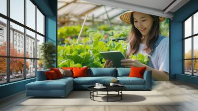 Smart farm sensor technology smart agriculture concept Smart young asian farmer girl using tablet to check quality and quantity of organic hydroponic vegetable garden at greenhouse in morning. Wall mural