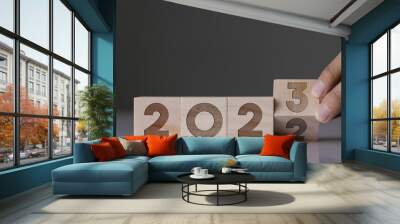 Concept of new beginning and start in 2023, Set goals for success, Plan business strategy for excellence goals, A year of change for good, Businessman hand flip wooden cubes with words 2022 to 2023. Wall mural