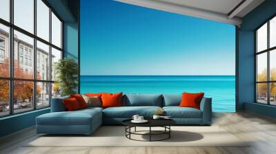 A calm and inviting turquoise ocean meets a clear, blue sky, creating a tranquil and refreshing scene on a bright, sunny day. Wall mural