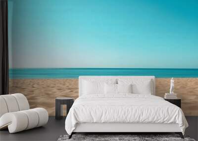 An expansive view of an endless sandy beach leading to a calm, serene blue horizon under a clear, cloudless sky, evoking peace and tranquility. Wall mural