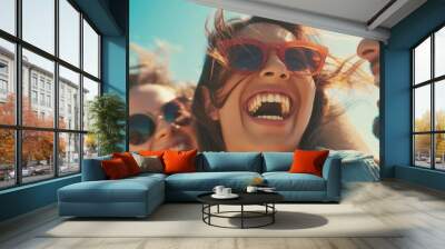 Group of friends wearing sunglasses, laughing joyfully on a sunny beach day, showcasing their vibrant and carefree summer moments. Wall mural