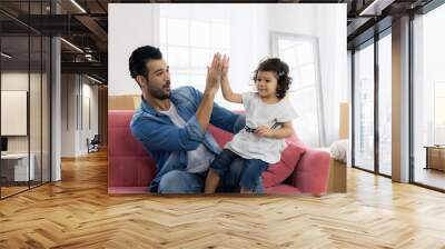 Happy family moment in the house. Father and daughter relaxing on red sofa. The family just moving in new house. Wall mural