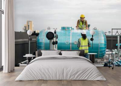 Two Professional engineer man and women working checking and maintenance pipeline construction top of the building. Worker in safety uniform using tablet at pipeline construction system Wall mural