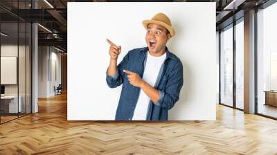 Young asian man with hat feels shock and surprise with overly face expression and looking on blank space. Wall mural