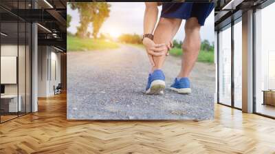 Runner sportsman holding leg in pain after suffering muscle injury during running workout training. Wall mural