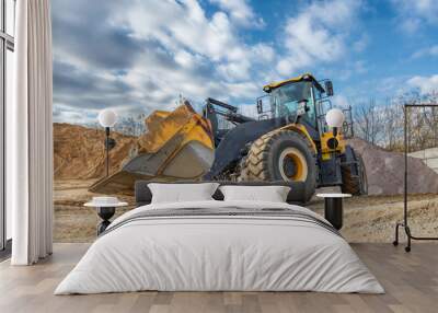 A wheel loader travels through a sand and gravel warehouse. Wall mural