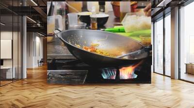 Chef cooking with flame in a frying pan on a kitchen stove, Chef in restaurant kitchen at stove with pan Wall mural