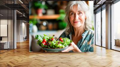 Elderly Woman Holding Fresh Garden Salad in Kitchen. Wall mural