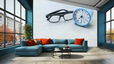 Alarm clock and eyeglasses on wooden table  Wall mural