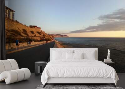 Asphalt road along the sea at sunset. Wall mural