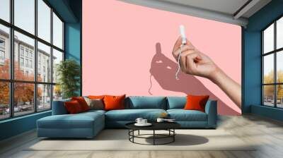 Woman's hand holding a clean cotton tampon on the pink background. Direct light. Wall mural