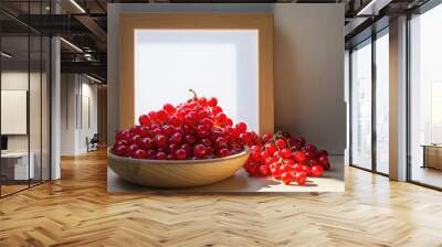 A bowl of red berries sits on a table next to a wooden frame Wall mural