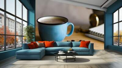 Black coffee in Blue cup on freshly roasted coffee beans background. Top view. Wall mural