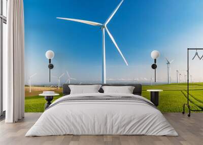 Large wind turbines generating electricity in a green field under a clear sky. Wall mural