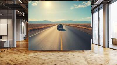 A lone car driving on an open road in the desert Wall mural