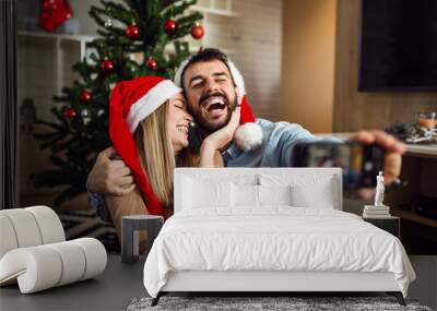 Cute young love couple make selfie with phone at Christmas time Wall mural