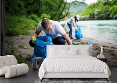 Group of young volunteers cleaning river shore Wall mural