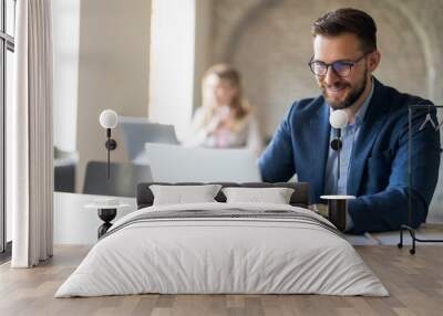 Smiling manager working on laptop at desk Wall mural