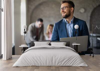 Well dressed businessman with laptop at office Wall mural