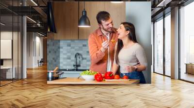 Young couple cooking together in kitchen Wall mural