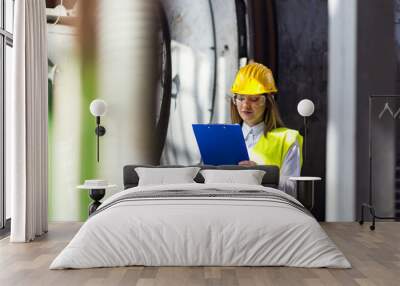 Young female engineer using clipboard.Female quality inspector at factory Wall mural