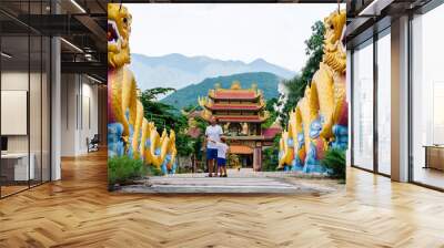 Dad and son tourists in buddhist temple Vietnam. Chinese golden dragon statue Wall mural