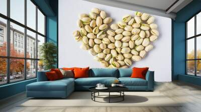 Closeup dried Pistachios nut as heart shape on wooden plate and white background for loving in Valentine's Day. Wall mural