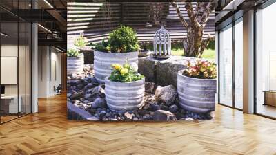 Stone garden arrangement with spring flowers in large concrete plant pots and decorative bird cage and bird bath details Wall mural