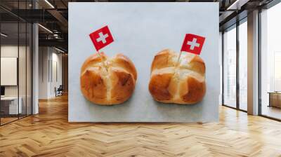 Swiss national holiday celebrated annually in Switzerland on August 1st with traditional bread called in German language Augusteggen. Two buns with cut cross shape and swiss flags. Wall mural