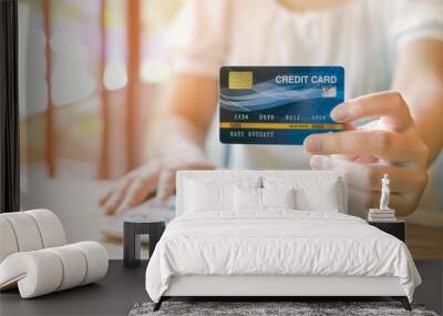 Women with credit card and using mobile phones to shop online. Close up card. Warm tones. Wall mural