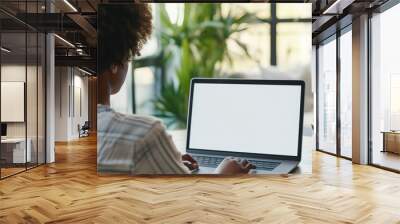 Over shoulder shot of a young woman using computer laptop in front of an blank white computer screen in home Wall mural