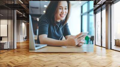 Young happy asian millennial woman listening music with her smartphone and wearing earphones, lifestyle concept Wall mural