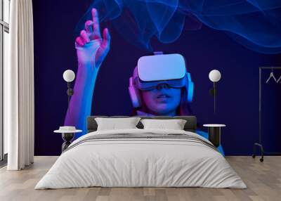 Woman is using virtual reality headset to access in metaverse. Wall mural